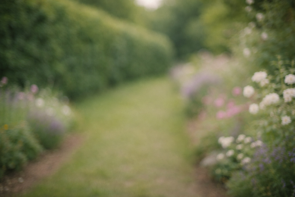 Baggrundsbillede til testimonials – roligt, let sløret billede af grøn hæk og blomster langs en havegang, med god plads til tekst ovenpå.